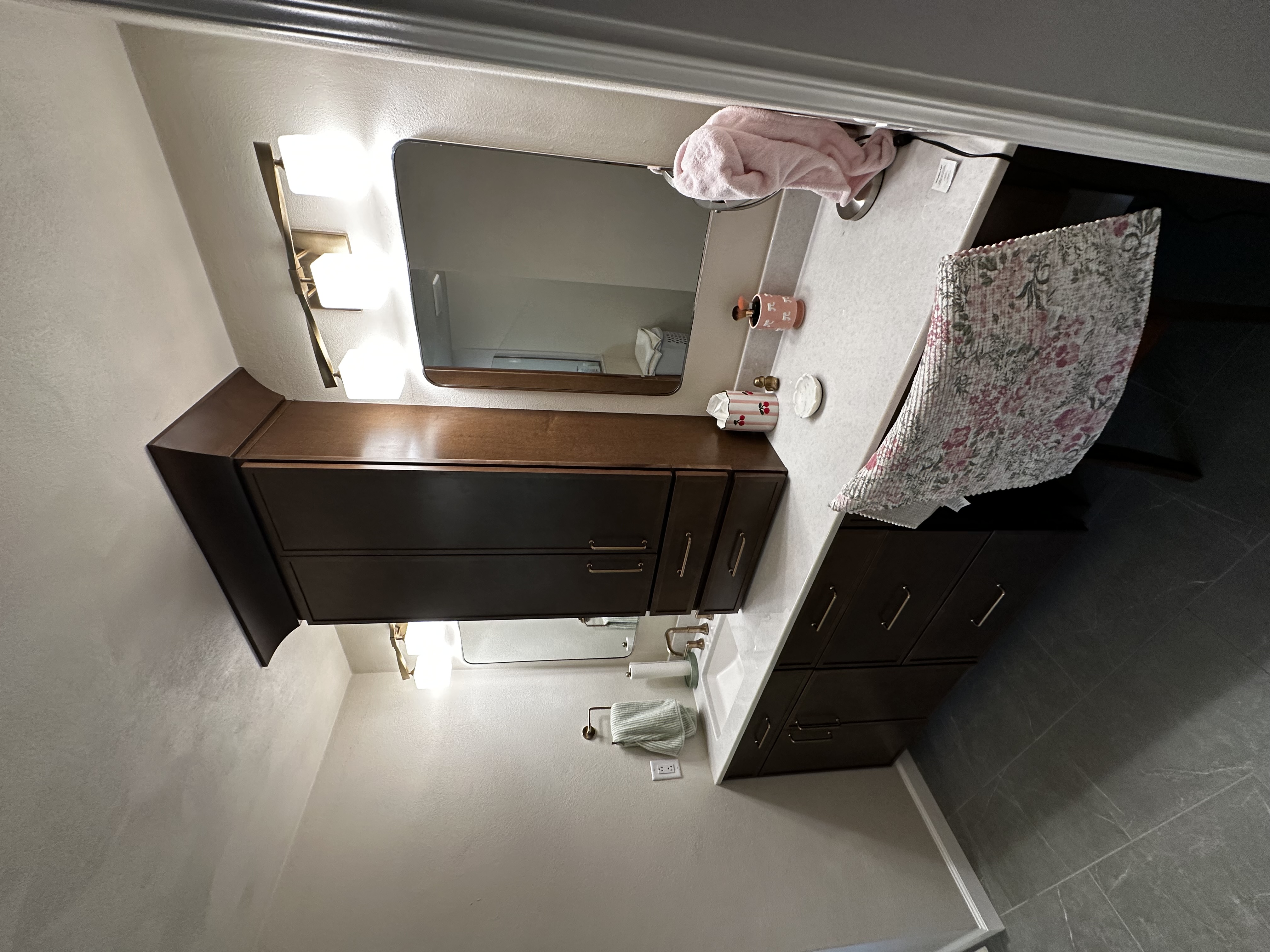 Completed bathroom vanity with custom dark wood cabinetry, dual mirrors, and new lighting